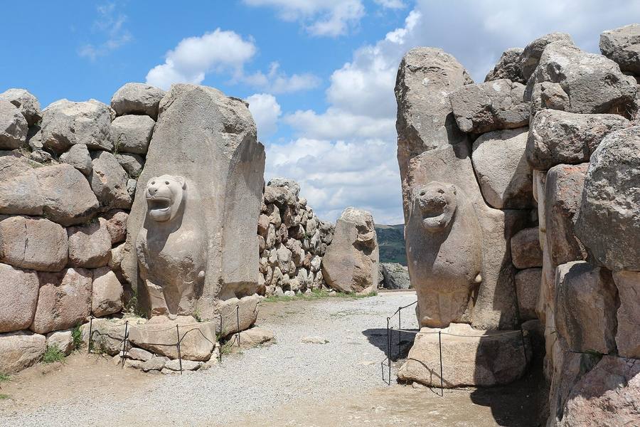 Puerta en una muralla de grandes bloques de piedra, flanqueada por dos leones esculpidos