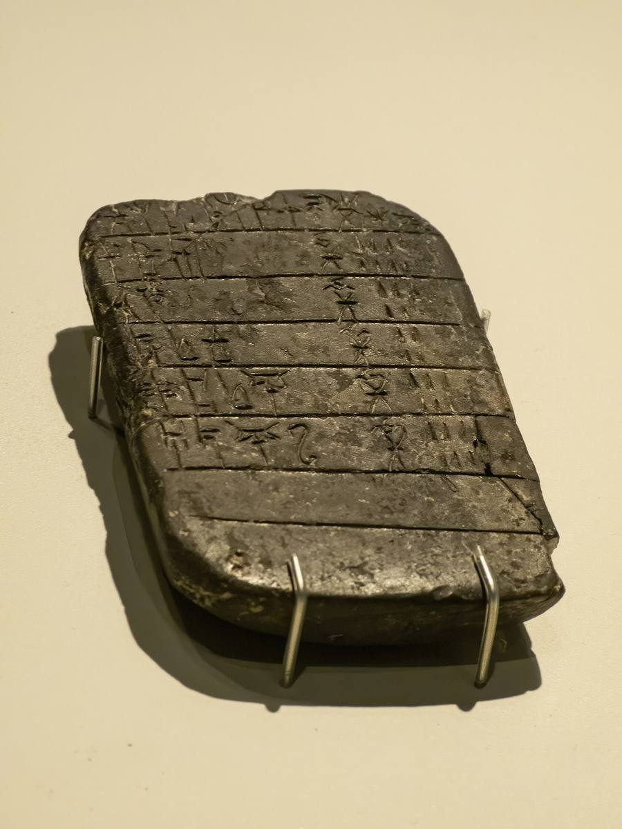 Tablilla de arcilla oscura con renglones incisos de signos en lineal B